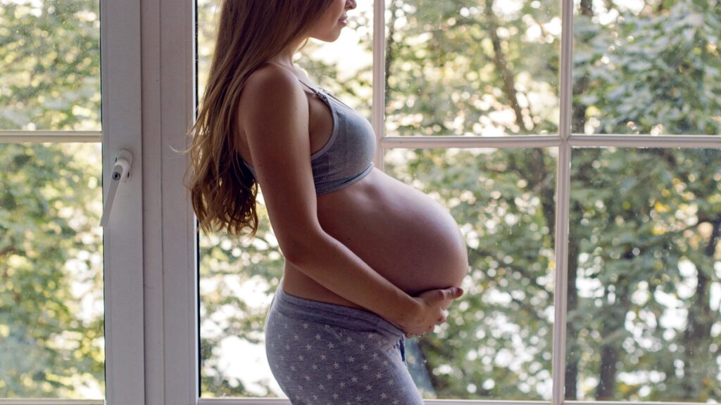 Gestante acariciando a barriga para sentir o bebê.