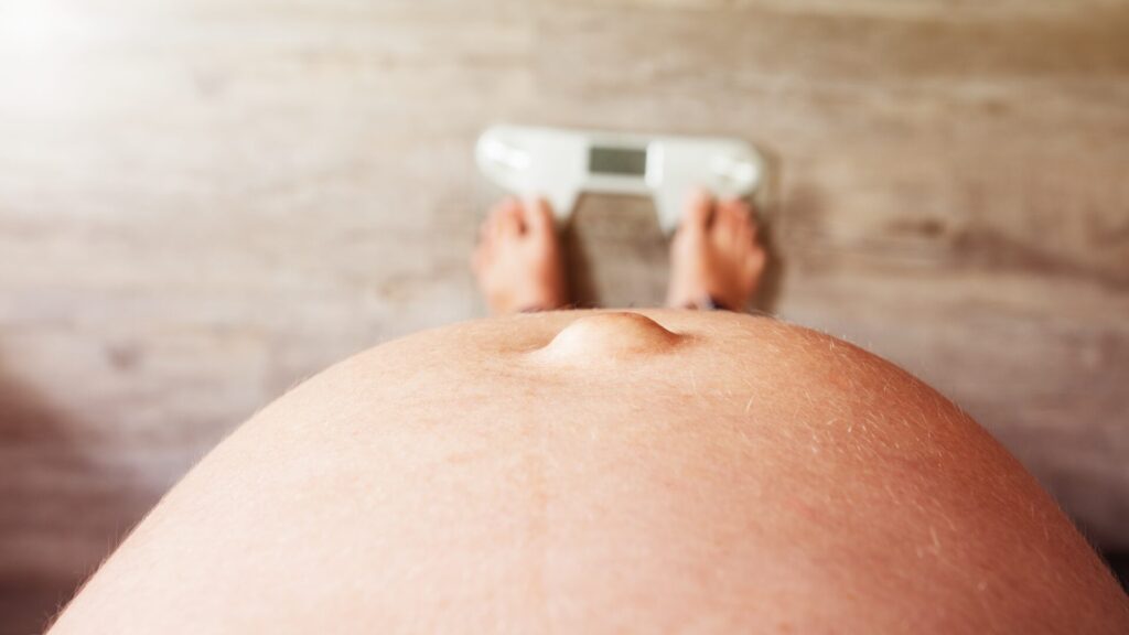 Gestante verificando seu peso em uma balança.